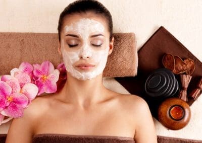 Young woman relaxing with cosmetic mask on face at beauty salon- indoors